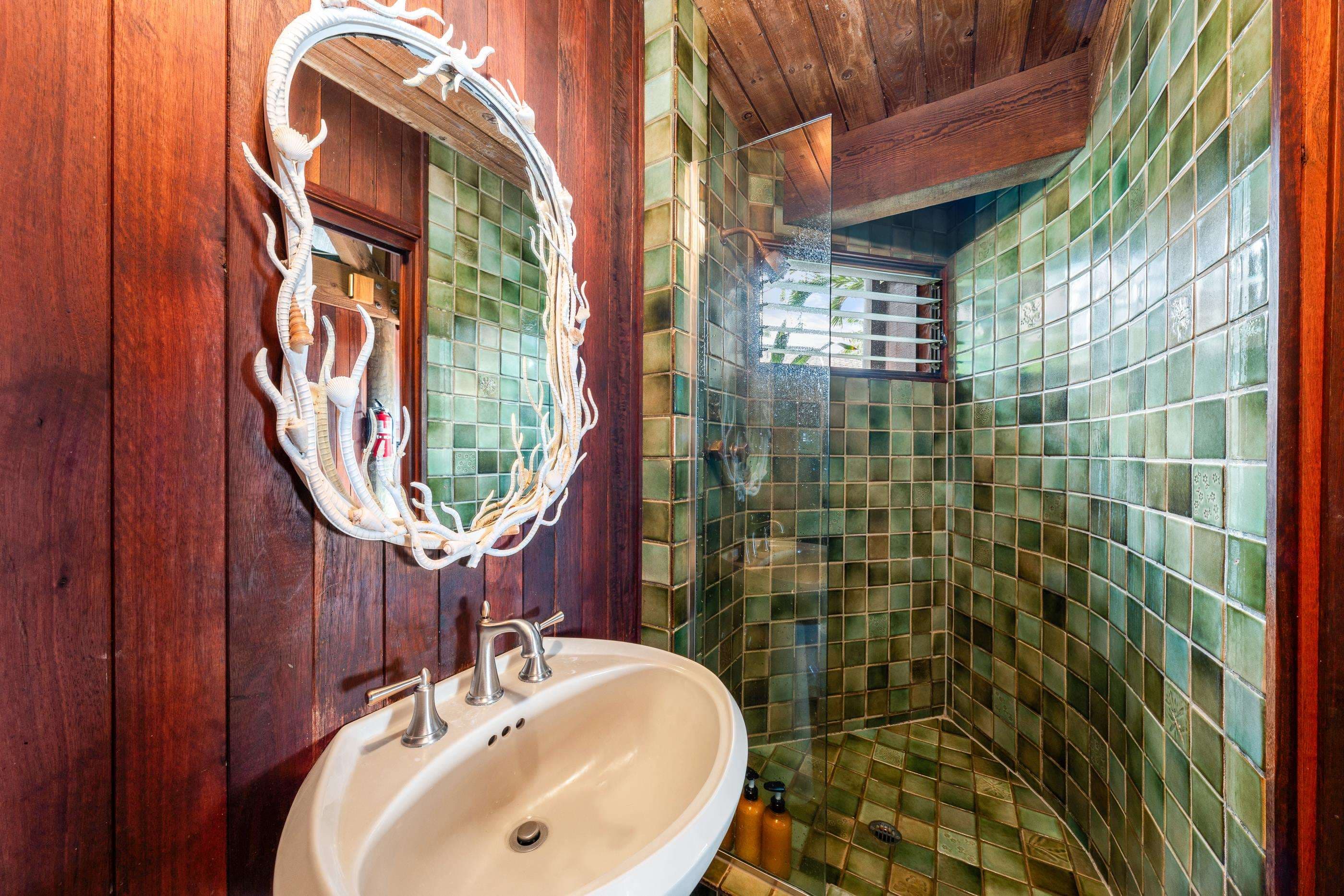 Powder room with a pedestal sink, coral-branch mirror on the green tilework