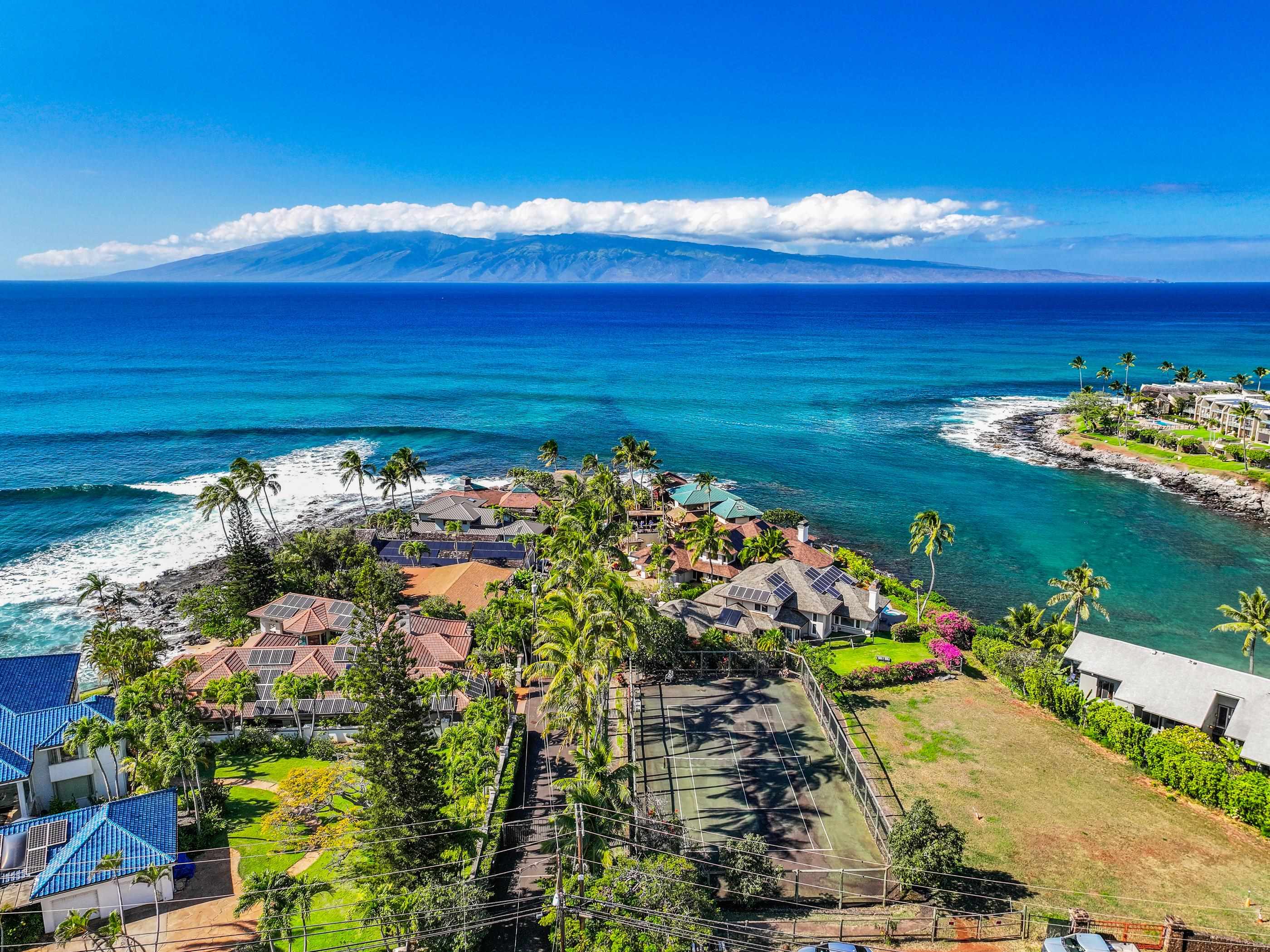 Aerial across the channel to Molokai, the point's palms and rooftops in the foreground
