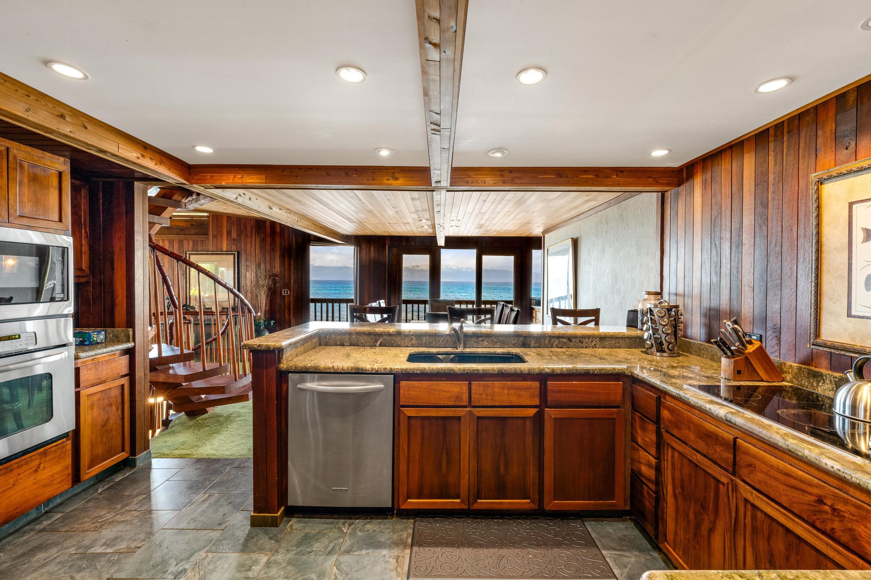 The full kitchen: stainless appliances, stone counters and the spiral stair beyond