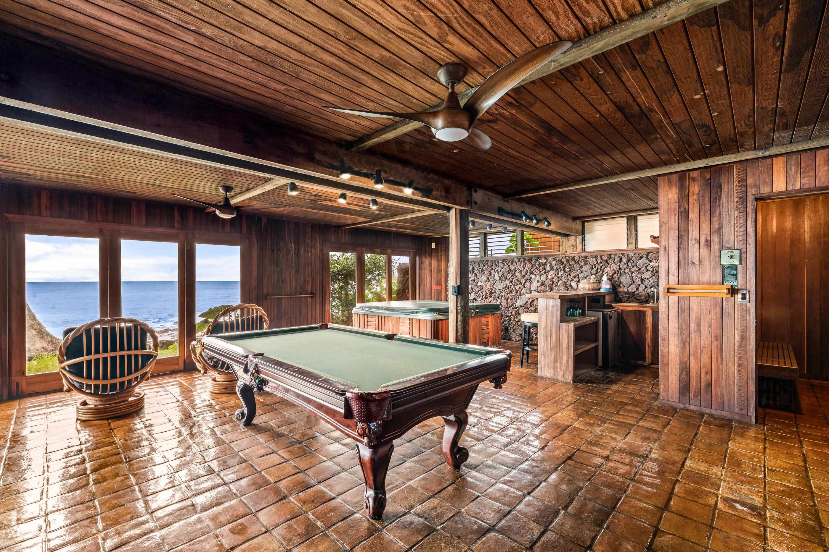 Game room wide open to the lawn: pool table, papasan chair and the bar behind