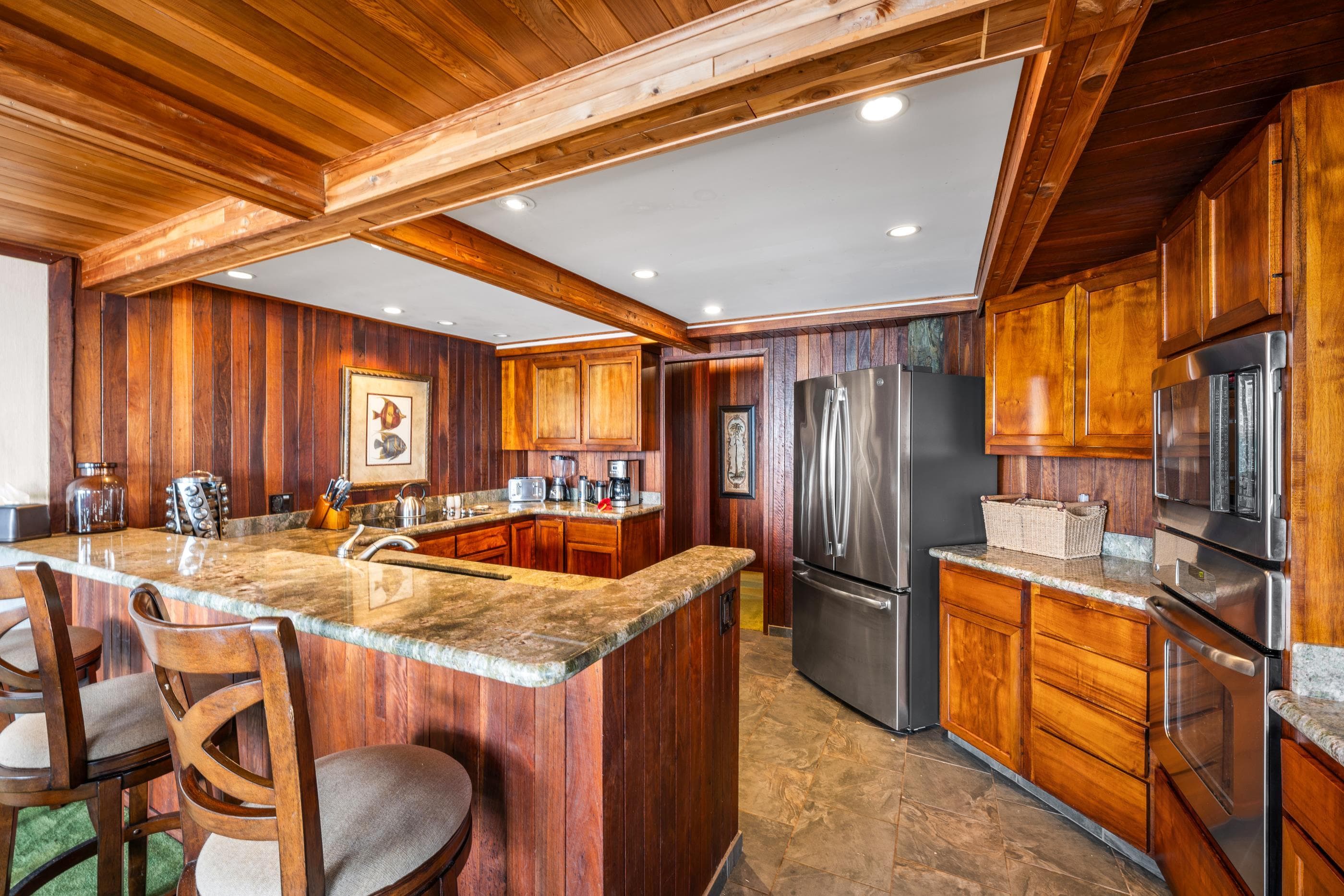 Kitchen bar seating at the granite counter, stainless refrigerator and double ovens behind
