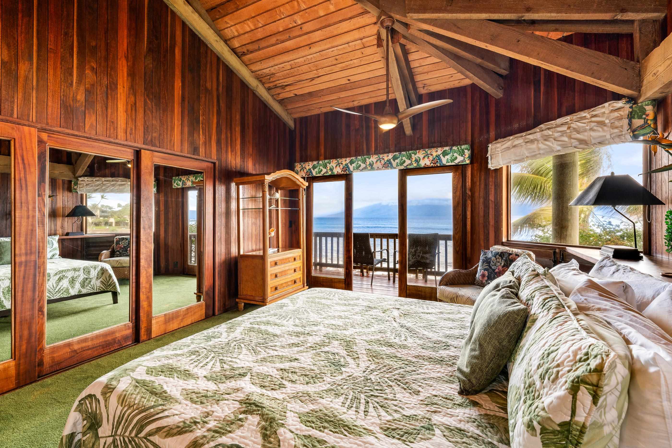 Bedroom with mirrored closets and ocean-view windows, palm-leaf bedding on the king bed